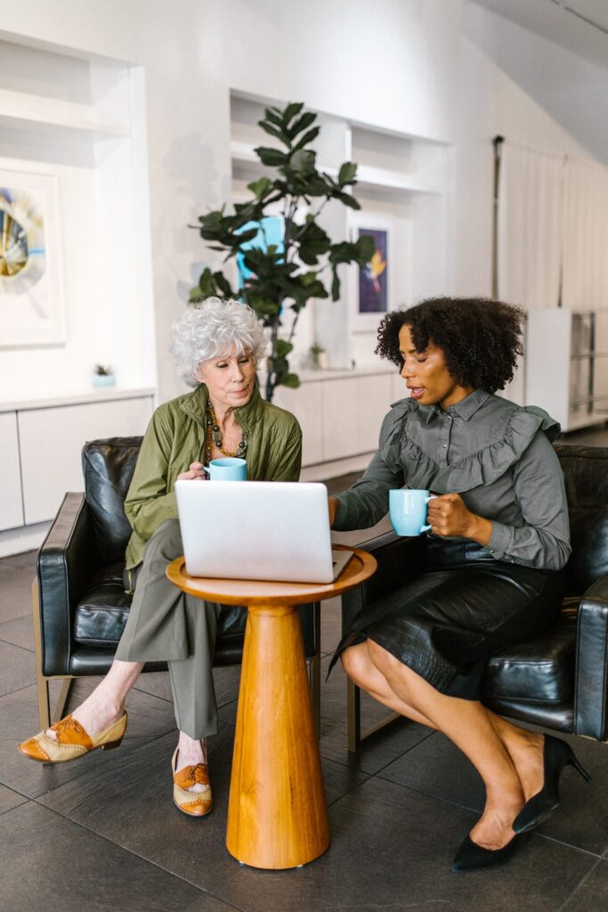 Two colleagues discussing ideas together over a laptop and coffee.