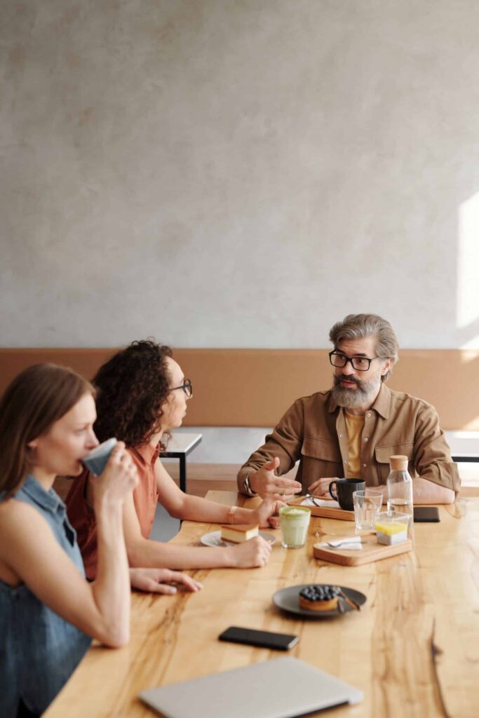 Three colleagues talking over coffee at a café table.